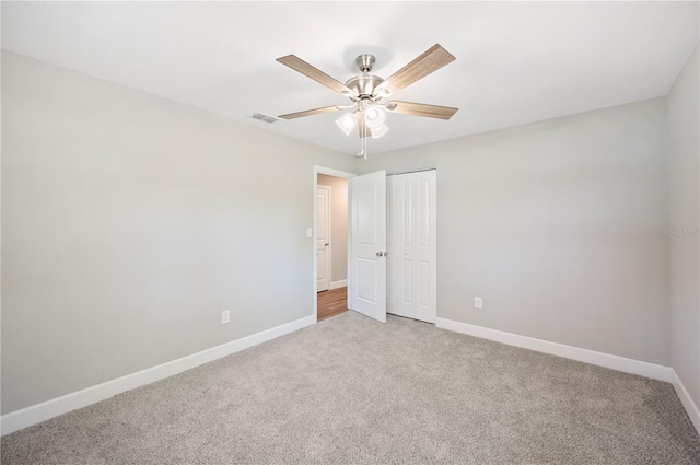 unfurnished bedroom featuring visible vents, light carpet, a closet, baseboards, and ceiling fan