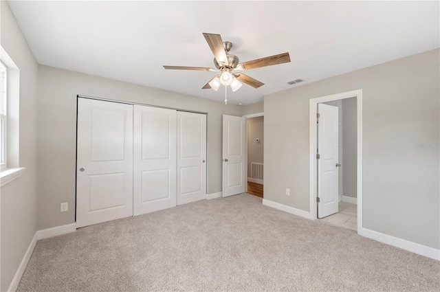 unfurnished bedroom with visible vents, light carpet, a ceiling fan, a closet, and baseboards