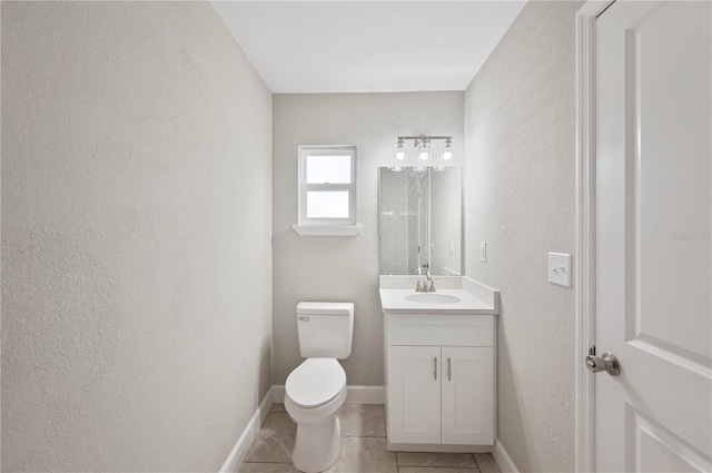 bathroom with tile patterned floors, toilet, baseboards, vanity, and a textured wall