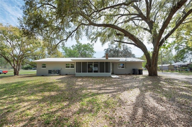 rear view of property with a yard, central AC unit, a sunroom, and a chimney