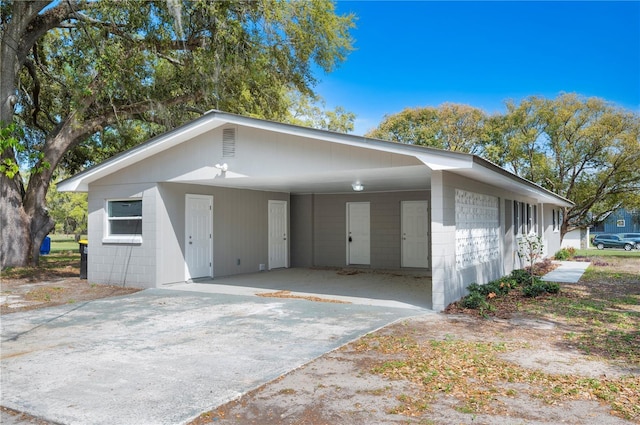 view of front of property featuring a carport, driveway, and concrete block siding