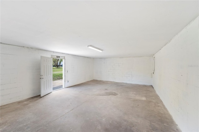 spare room featuring concrete block wall and concrete floors