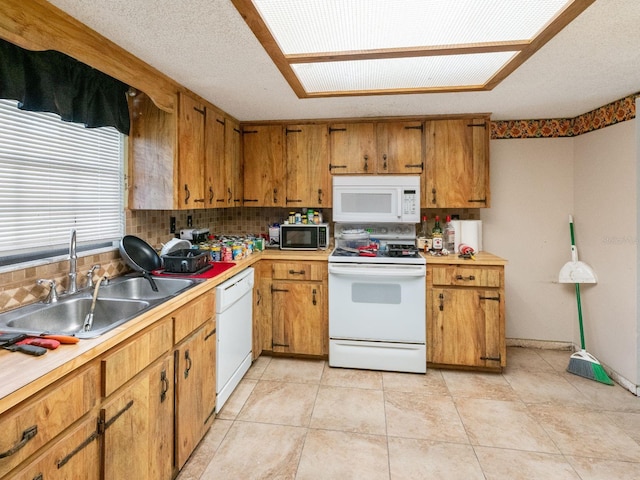 kitchen with tasteful backsplash, light countertops, brown cabinets, white appliances, and a sink