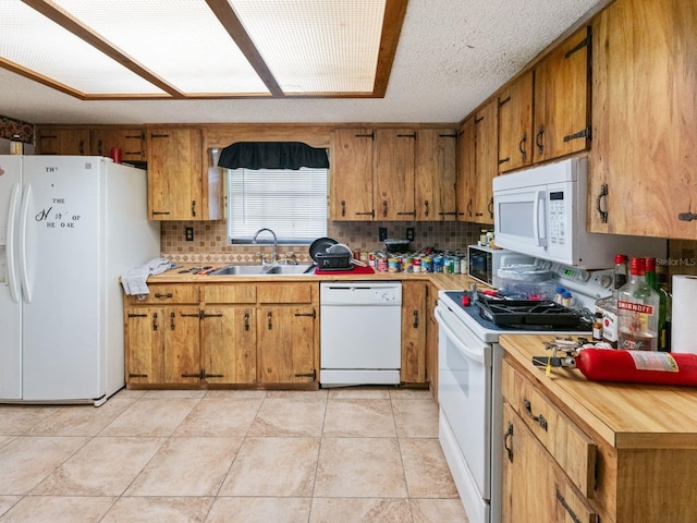 kitchen featuring white appliances, tasteful backsplash, brown cabinets, and a sink