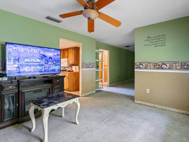 living room featuring visible vents, baseboards, a textured ceiling, and a ceiling fan