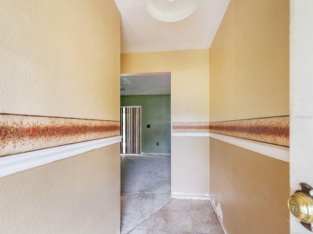 hallway featuring light tile patterned floors and a textured ceiling