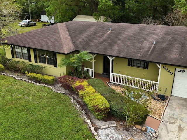 ranch-style home with a shingled roof, a porch, a front yard, and stucco siding