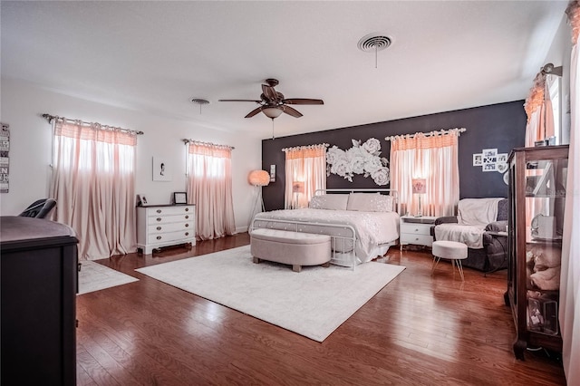 bedroom with visible vents, dark wood-type flooring, and a ceiling fan