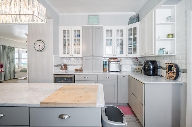 kitchen with ornamental molding, open shelves, backsplash, wine cooler, and glass insert cabinets