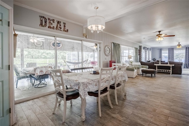 dining space featuring crown molding, ceiling fan with notable chandelier, and wood tiled floor