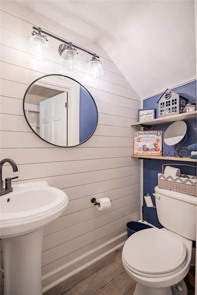 bathroom with wood finished floors, toilet, wooden walls, and vaulted ceiling