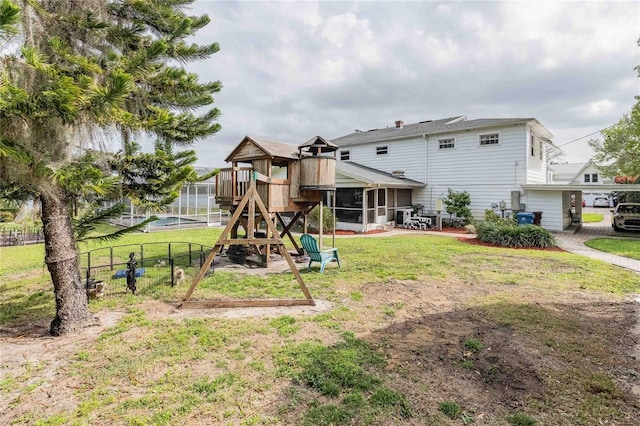 exterior space featuring a playground, a yard, fence, and a sunroom