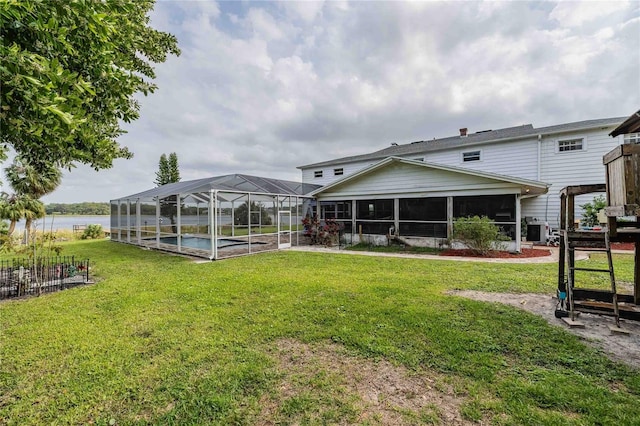 back of property with a lanai, an outdoor pool, and a yard