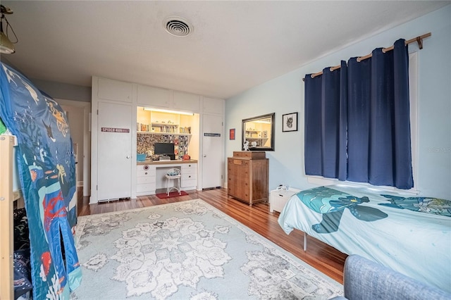 bedroom featuring wood finished floors and visible vents