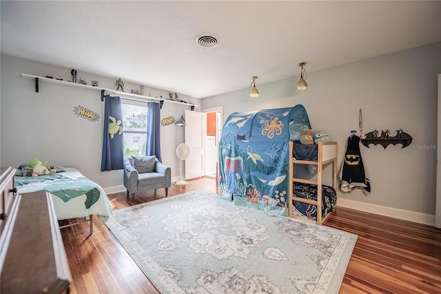 bedroom with visible vents, baseboards, and wood finished floors