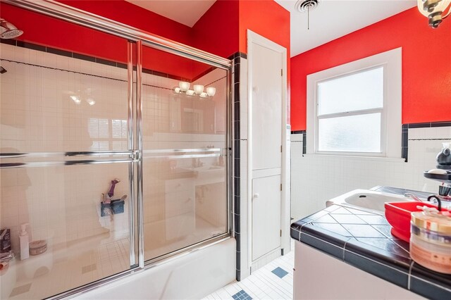 bathroom with vanity, a wainscoted wall, enclosed tub / shower combo, tile walls, and tile patterned floors