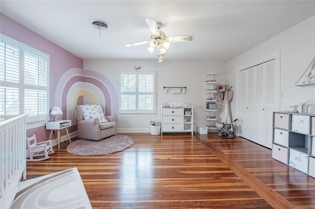 sitting room with visible vents, ceiling fan, baseboards, and wood finished floors