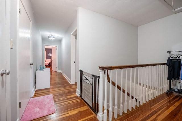 corridor featuring an upstairs landing, baseboards, and wood finished floors