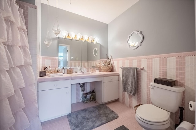 full bathroom with a wainscoted wall, toilet, tile walls, tile patterned flooring, and vanity