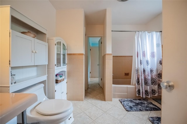 full bathroom with a wainscoted wall, shower / tub combo with curtain, toilet, tile walls, and tile patterned flooring