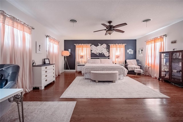 bedroom with dark wood finished floors, a ceiling fan, and visible vents