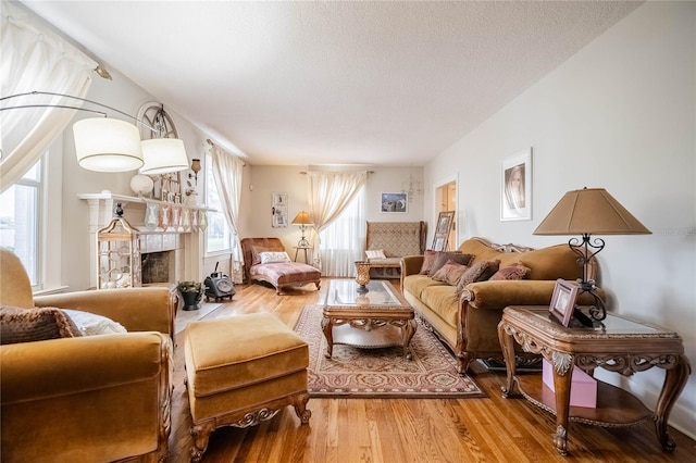 living room featuring a fireplace, a textured ceiling, and wood finished floors