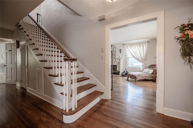 stairway featuring baseboards, wood finished floors, and a fireplace