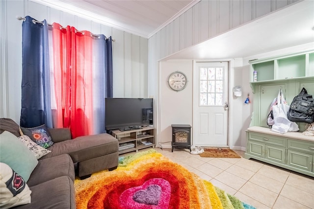 living area featuring light tile patterned flooring, crown molding, and a wood stove