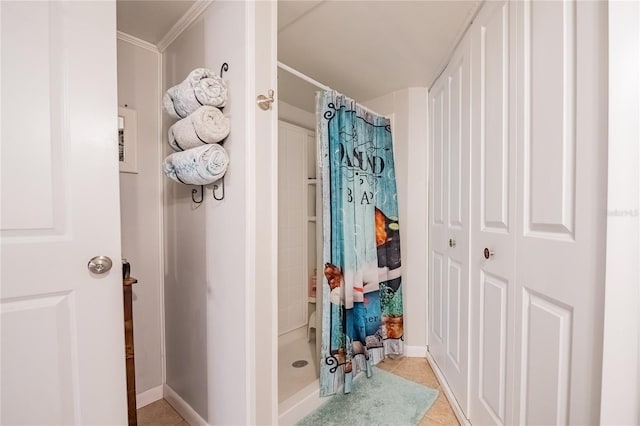 bathroom with tile patterned floors, a shower stall, crown molding, and baseboards