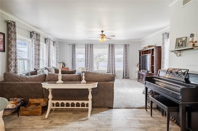 living area featuring visible vents, a healthy amount of sunlight, ornamental molding, and a ceiling fan