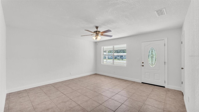 foyer featuring baseboards, visible vents, a textured ceiling, and a ceiling fan