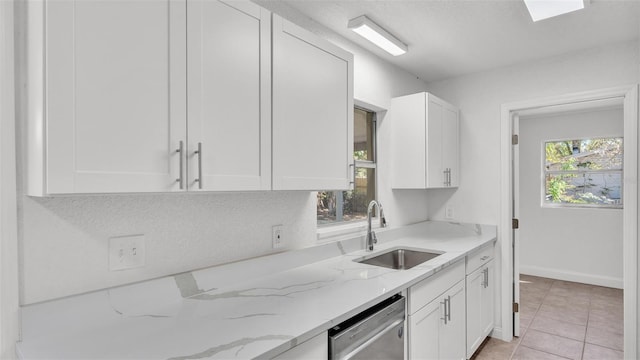 kitchen featuring a sink, white cabinets, light tile patterned floors, light stone countertops, and dishwasher