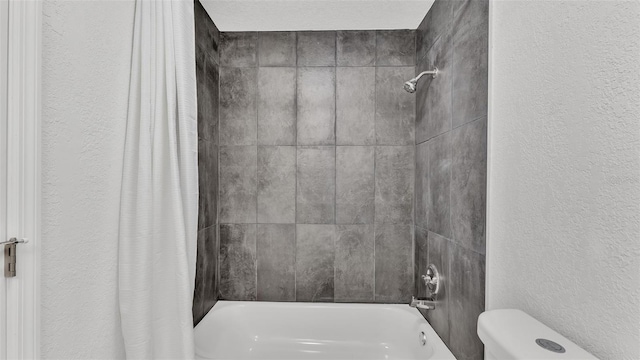 full bath featuring shower / bath combo with shower curtain, toilet, and a textured wall