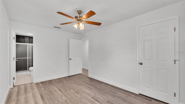 unfurnished bedroom featuring ensuite bath, visible vents, baseboards, and light wood-style floors