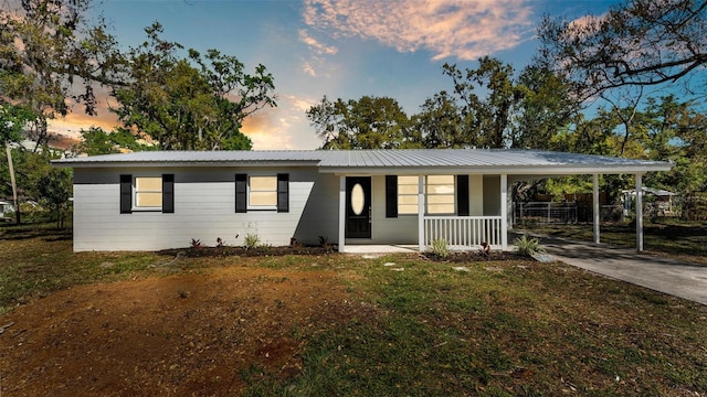 single story home with an attached carport, covered porch, driveway, and metal roof