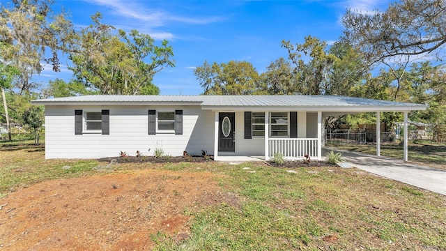 ranch-style home featuring driveway, fence, covered porch, metal roof, and a carport