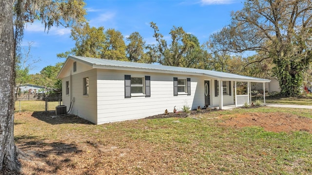 view of front of property featuring metal roof, cooling unit, a front lawn, and fence