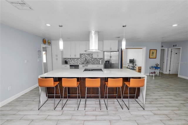 kitchen featuring visible vents, stainless steel fridge, white cabinets, exhaust hood, and tasteful backsplash