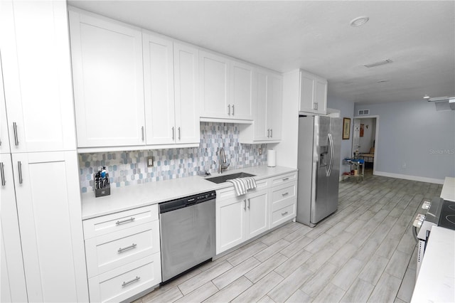 kitchen with light countertops, decorative backsplash, stainless steel appliances, white cabinetry, and a sink