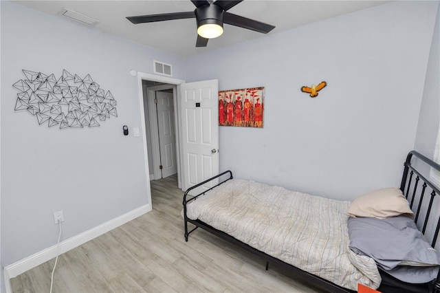 bedroom featuring light wood finished floors, visible vents, ceiling fan, and baseboards