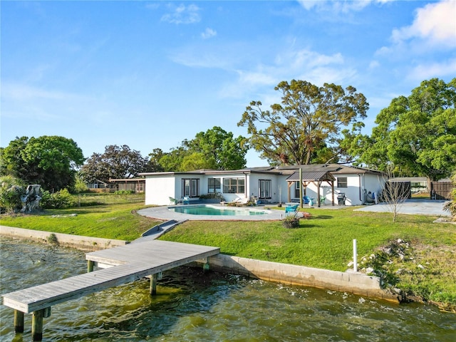 rear view of property featuring a patio area, a lawn, an outdoor pool, and a water view