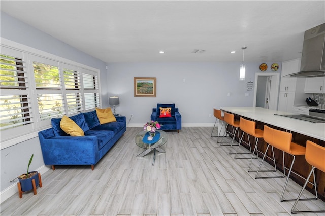 living room with light wood finished floors, recessed lighting, and baseboards