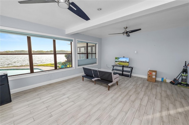 sitting room featuring beamed ceiling, a ceiling fan, baseboards, and light wood-style flooring