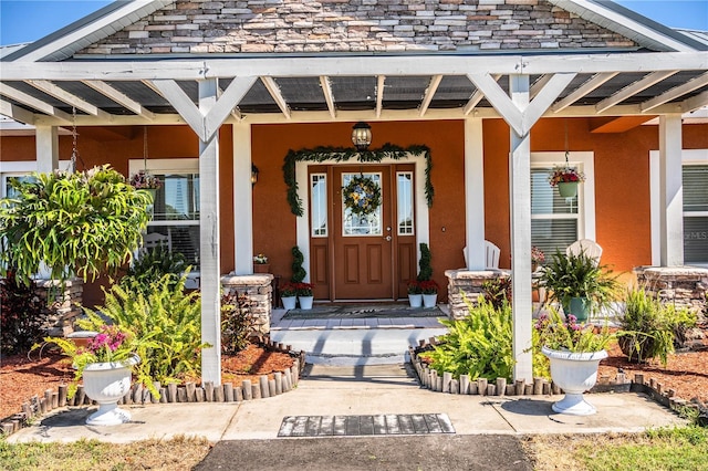 doorway to property with covered porch and stucco siding