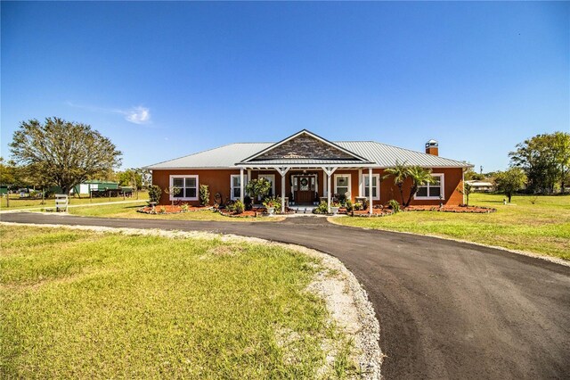 view of front of property featuring a front yard, a chimney, and metal roof