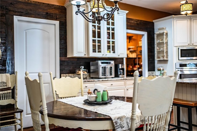 kitchen with glass insert cabinets, built in microwave, a chandelier, stainless steel oven, and white cabinetry