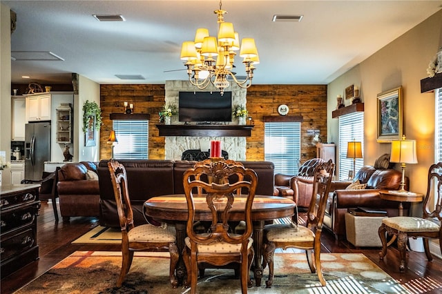 living area with a chandelier, visible vents, a stone fireplace, and hardwood / wood-style floors