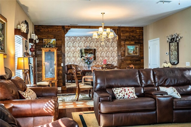 living area featuring visible vents, wood finished floors, wooden walls, a chandelier, and an accent wall