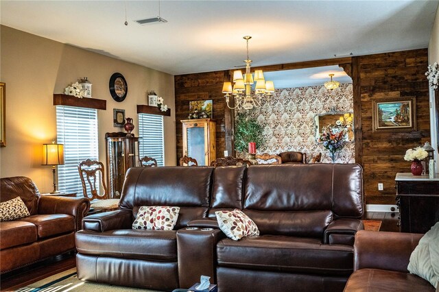 living area featuring an accent wall, visible vents, wood walls, and a chandelier