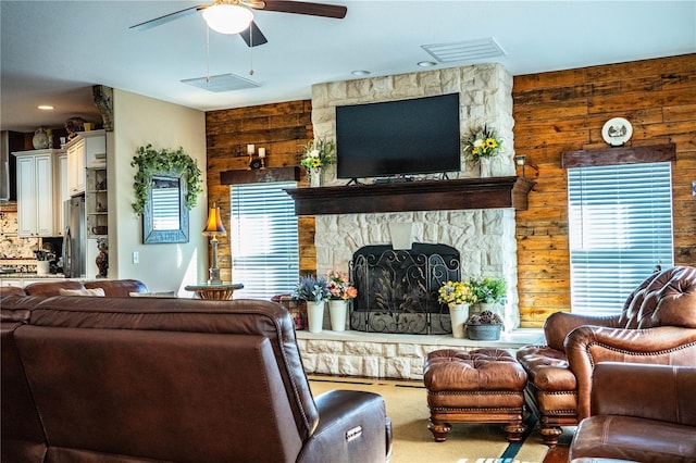 living room with visible vents, wooden walls, carpet, a fireplace, and ceiling fan